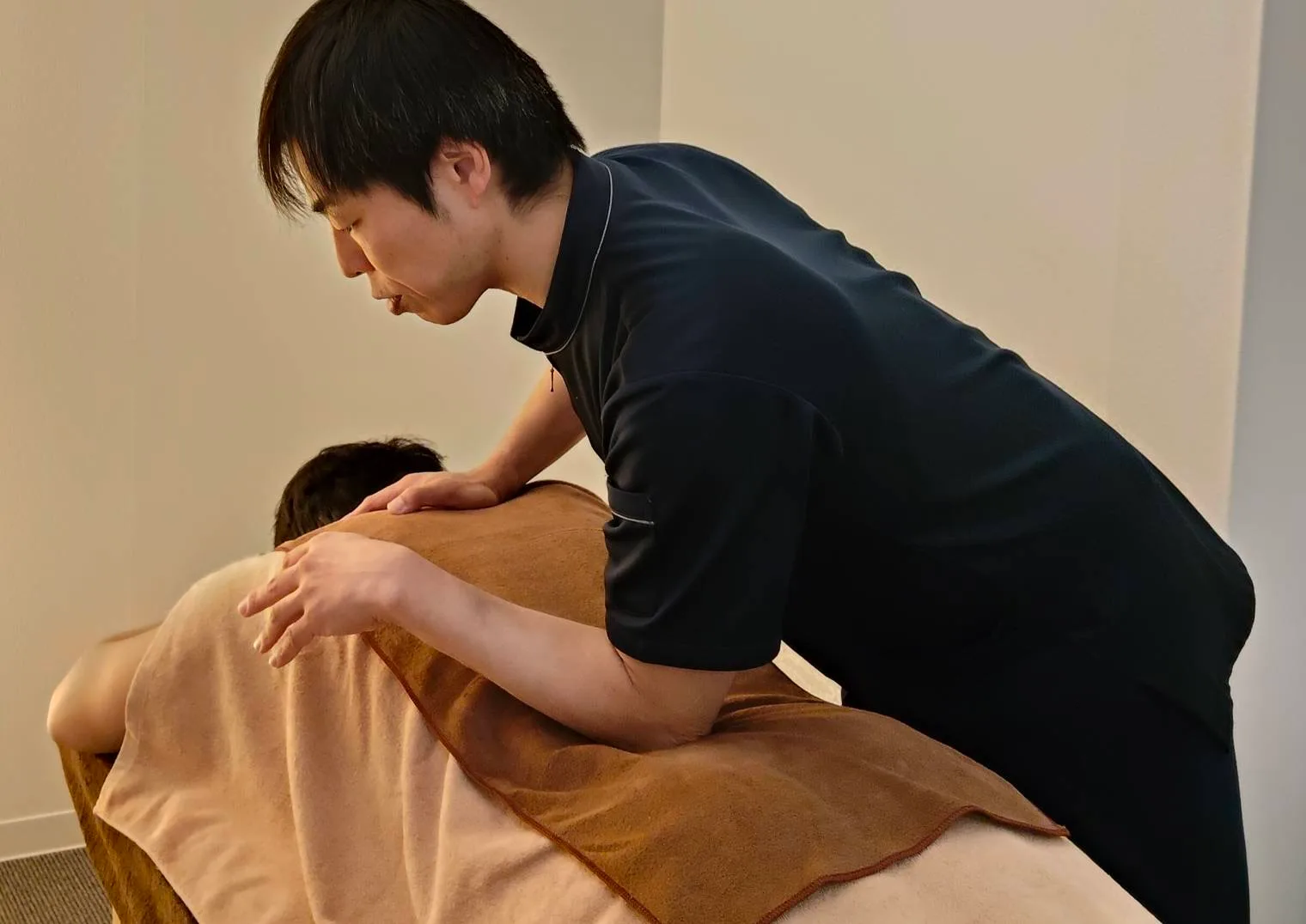 施術者が背中に手を添えて丁寧に施術している様子